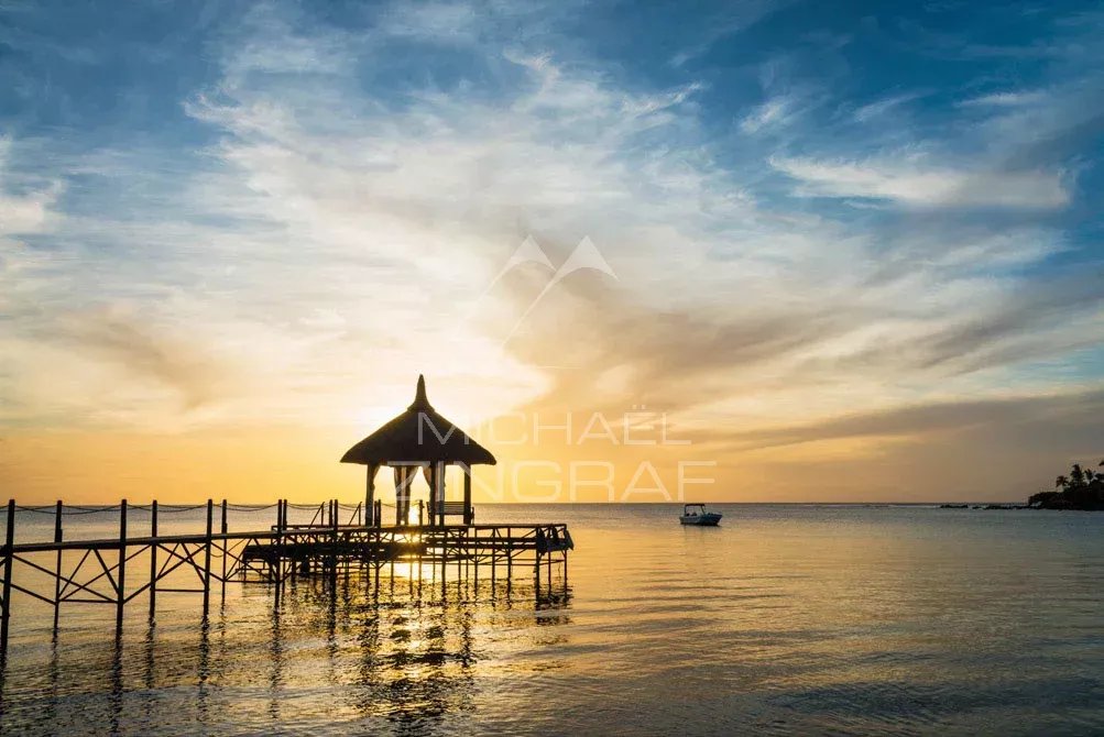 Sunset in Tamarin Sunset on a wooden pontoon with a shelter by the water in Tamarin.