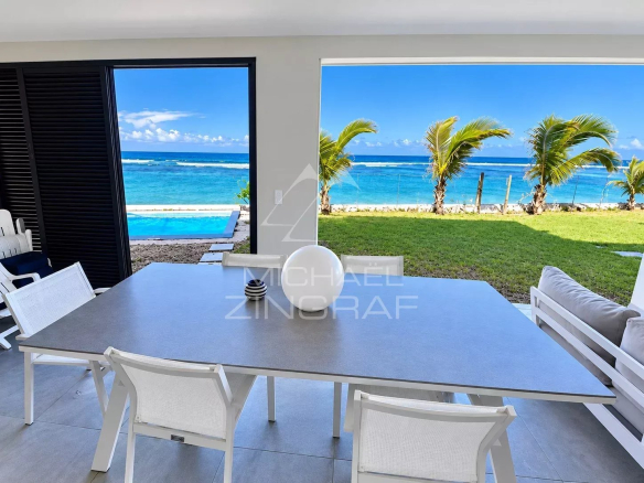 Terrasse d'un appartement avec vue sur le lagon à Saint-Pierre, tables et chaises blanches.