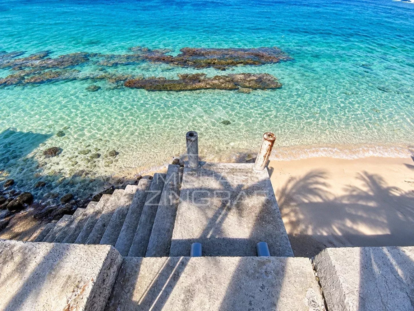 Accès direct à la plage depuis un appartement à Saint-Pierre, avec vue sur le lagon et les rochers.
