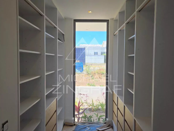 Intérieur d'une villa en construction avec des étagères et une vue sur l'extérieur.