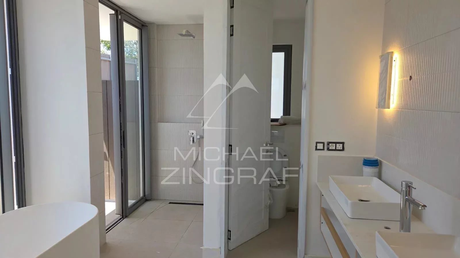Salle de bain moderne avec douche et lavabo, en cours de construction dans une villa à Mont Choisy Golf.