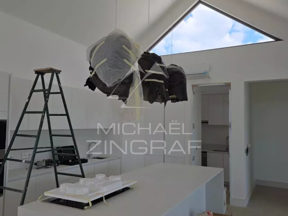 Intérieur d'une villa en construction avec cuisine moderne et éclairage suspendu.