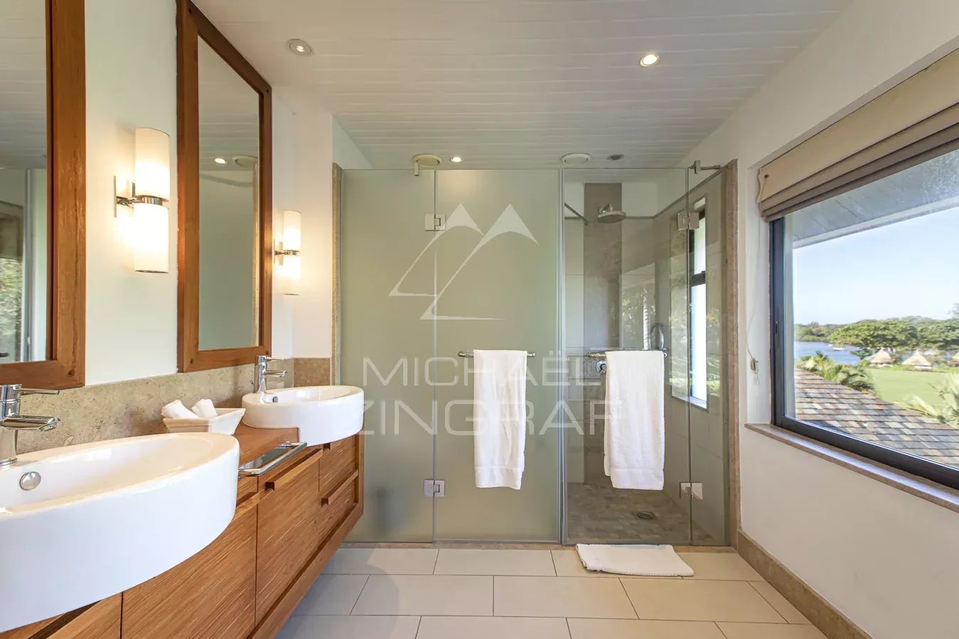 Salle de bain de la Villa Lunea Salle de bain moderne avec deux lavabos et douche en verre, vue sur le lagon