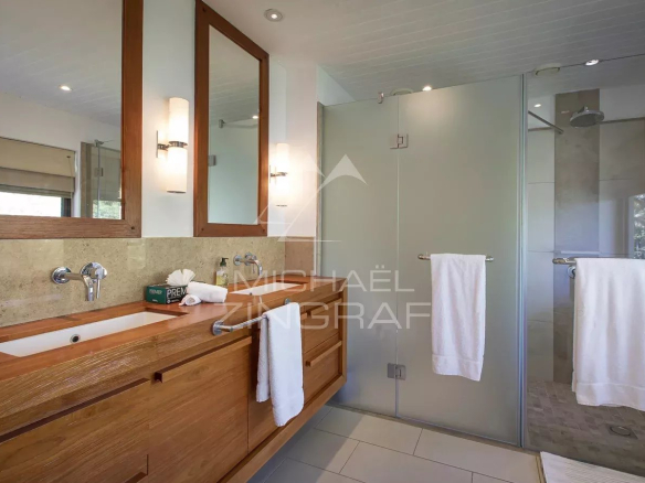 Salle de bain moderne avec lavabo en bois et douche vitrée dans une villa à l'Ile Maurice.