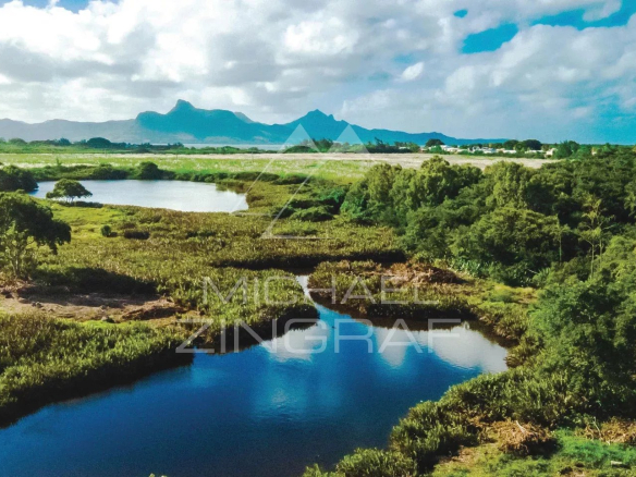 View of the natural ponds of Pointe d'Esny surrounded by greenery under a cloudy sky.