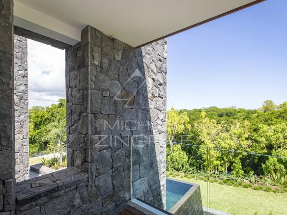 View from a modern villa with stone walls and access to a green outdoor space.