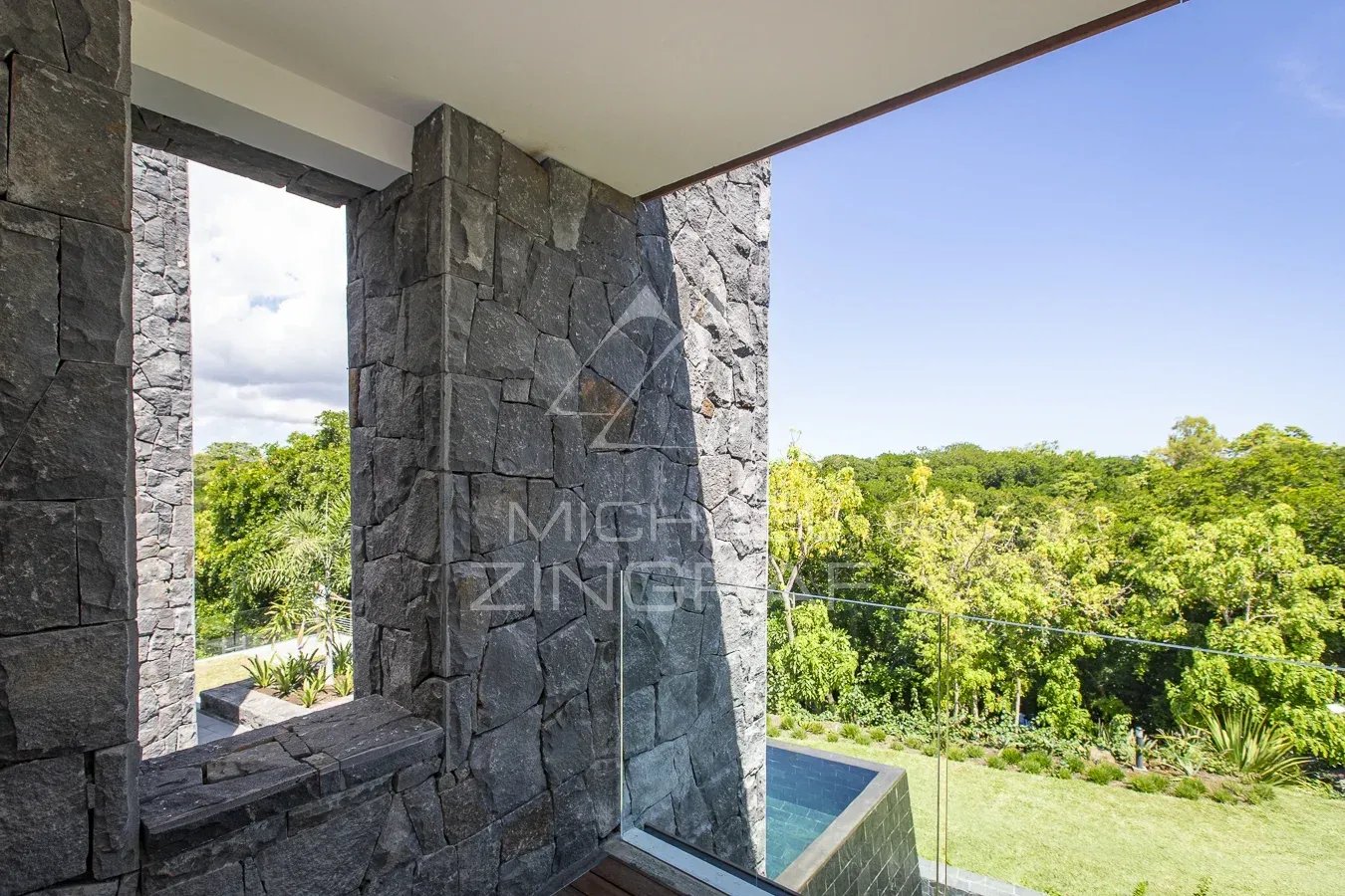 Luxury villa in Haute Rive View from a modern villa with stone walls and access to a green outdoor space.