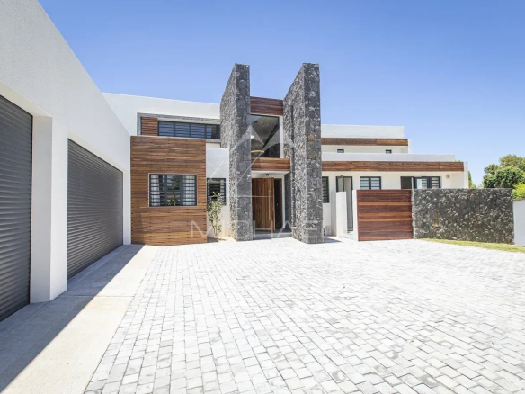 Modern villa with stone and wood facade, paved driveway in Haute Rive.
