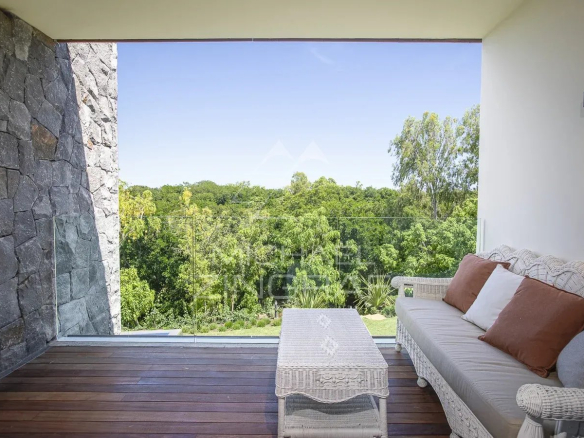 Terrace of a villa with views of the vegetation, wicker furniture, and natural light.