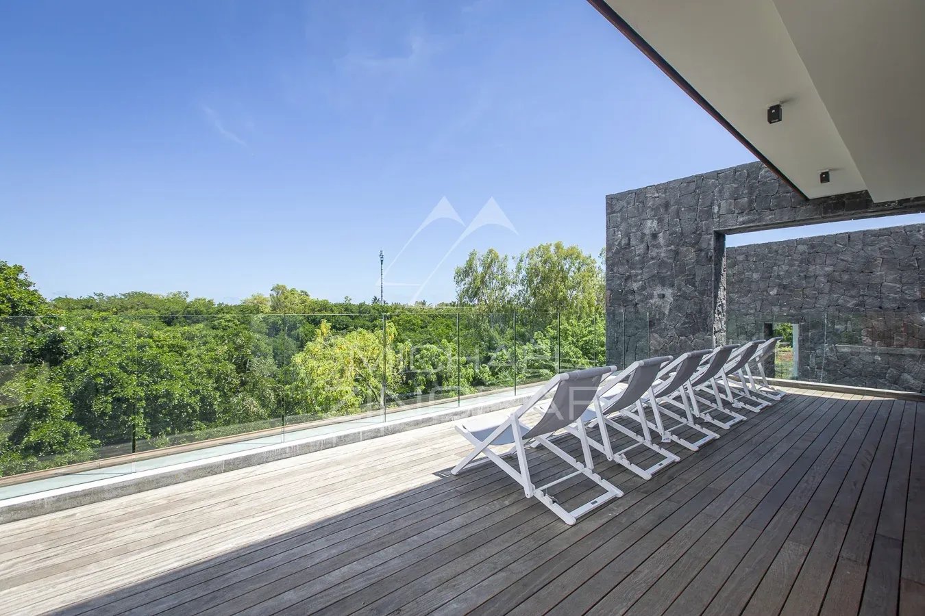 Terrace of the villa at Haute Rive Wooden terrace with sun loungers, overlooking the greenery and the swimming pool of the villa in Haute Rive.
