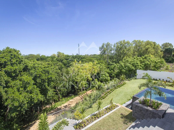 View of the private pool and garden of a villa in Haute Rive, Azuri, with trees in the background.