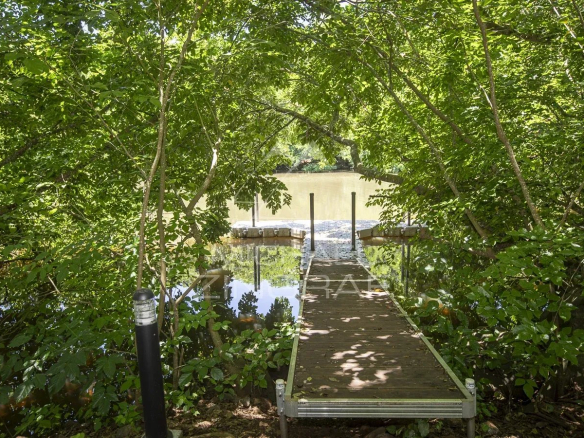 A quay surrounded by greenery leading to a calm river at Haute Rive.