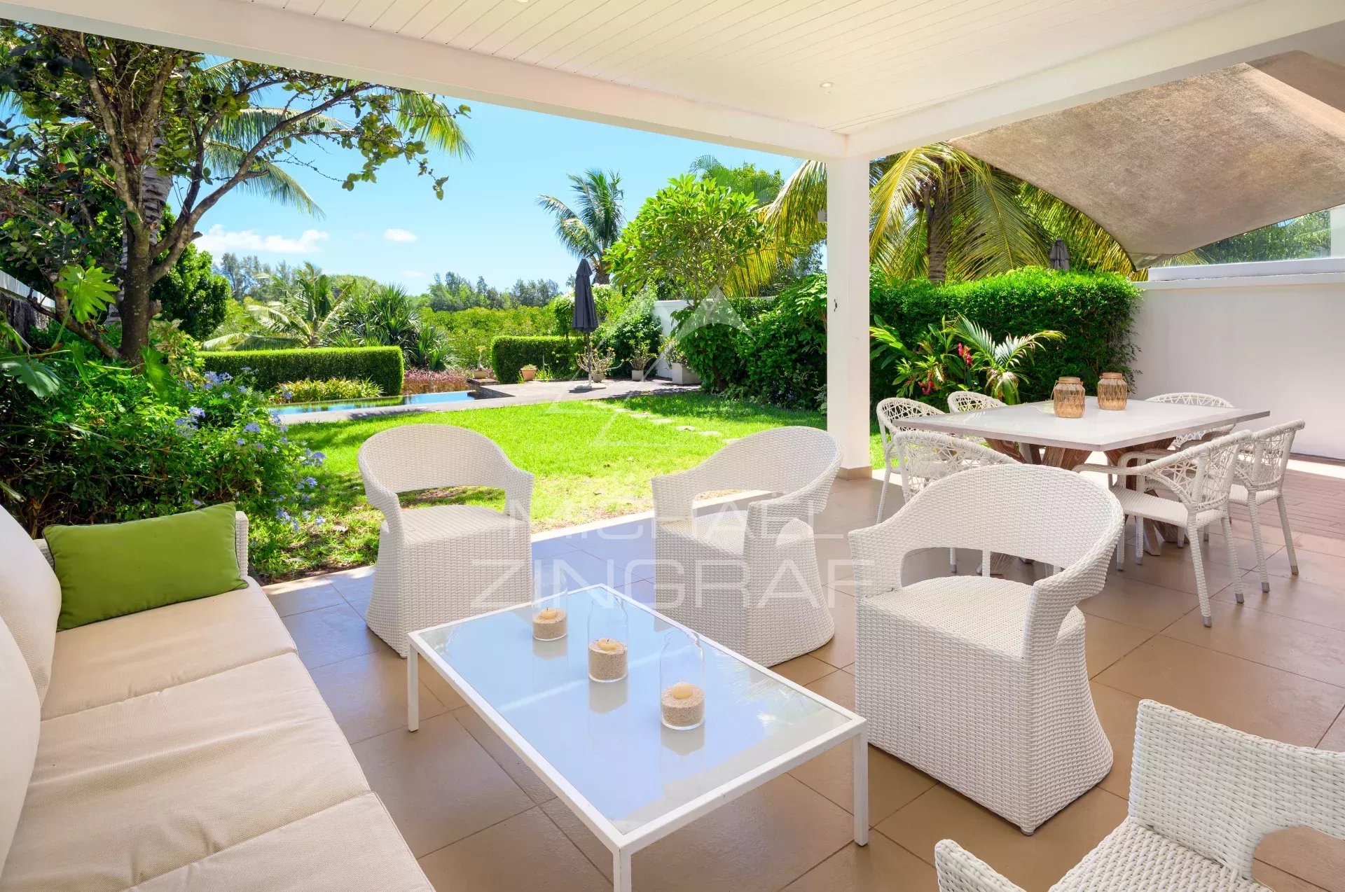 Terrasse d'un townhouse à Haute Rive avec mobilier en osier et vue sur un jardin verdoyant.
