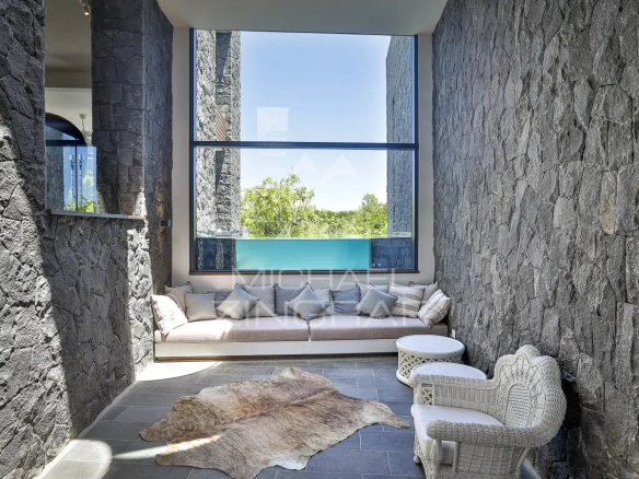 Intérieur d'une villa moderne avec murs en pierre et coin salon lumineux.