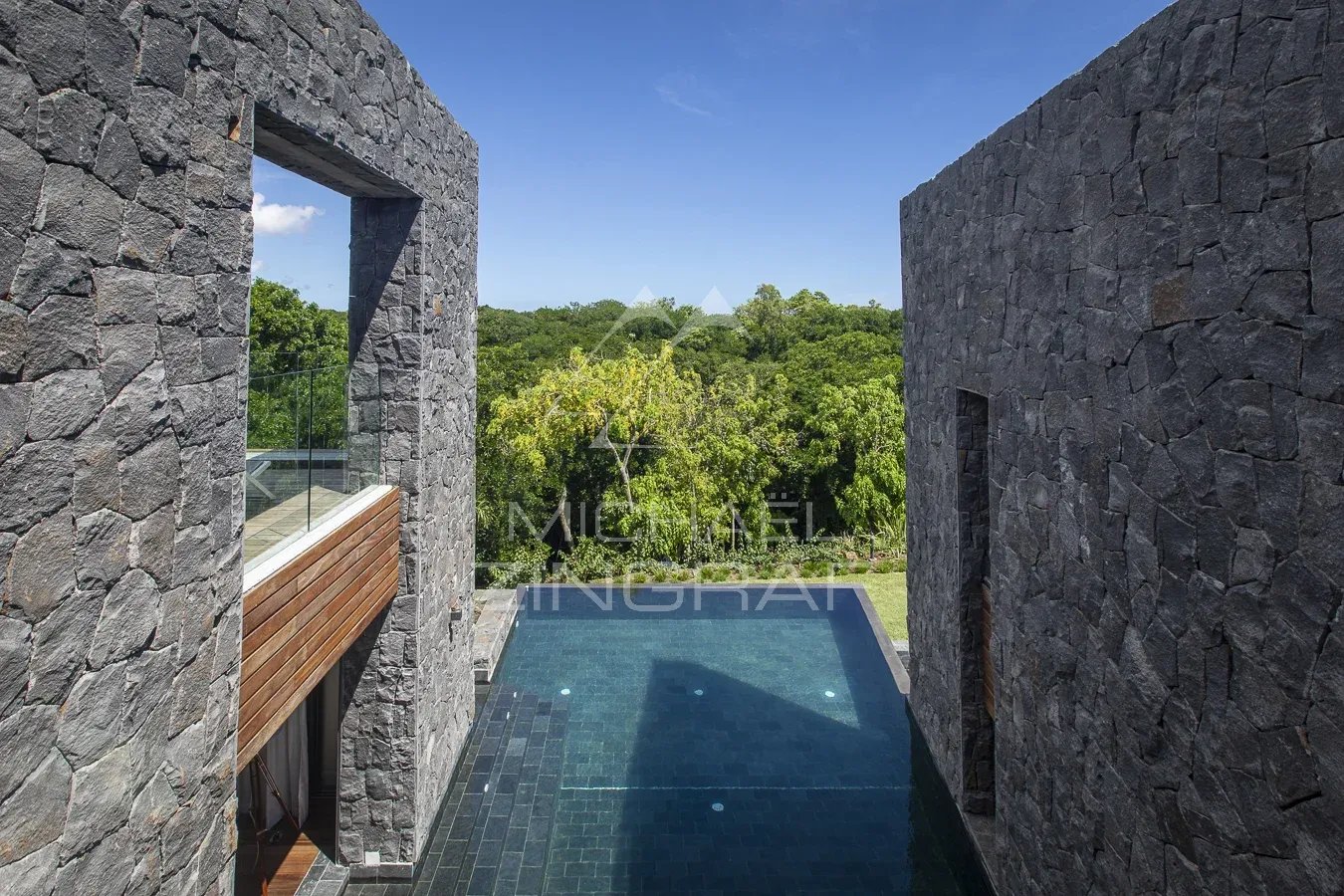 Villa de prestige avec piscine à Haute Rive Vue d'une villa moderne avec piscine à débordement et murs en pierre, entourée de verdure.