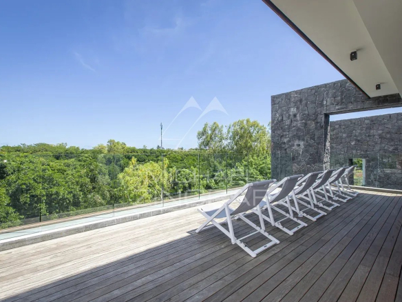 Terrasse d'une villa avec chaises longues, vue sur la nature environnante à Haute Rive.