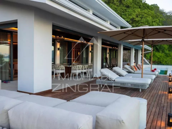 Terrasse d'une villa moderne avec transats et parasol, vue sur la nature à Rivière Noire, Île Maurice.