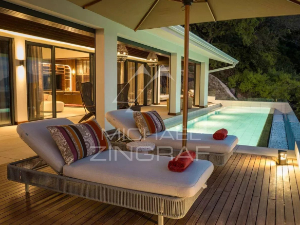 Terrasse avec chaises longues et piscine à débordement, vue sur la nature à Rivière Noire, Île Maurice.