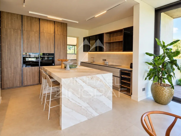 Modern and spacious kitchen in a contemporary villa with central island and garden view.