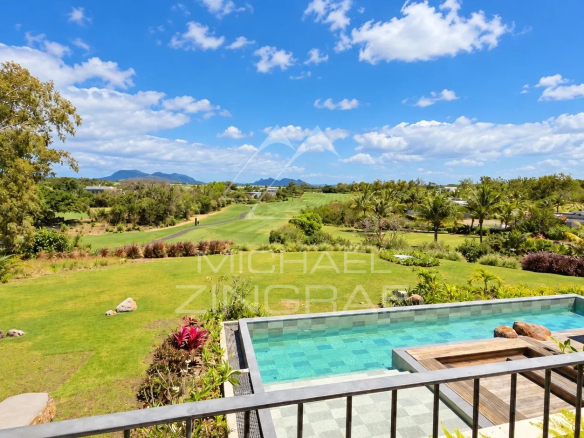 View of a golf course with a private pool and a lush garden, under a blue sky in Beau Champ.