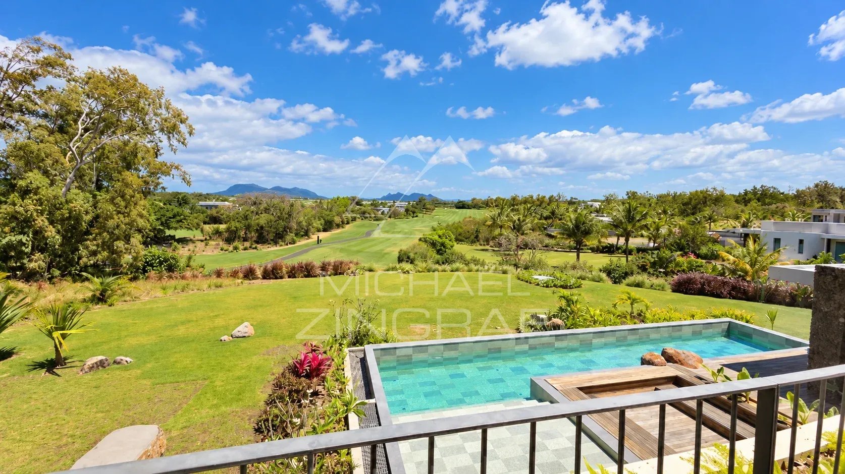 View of a golf course with a private pool and a lush garden, under a blue sky in Beau Champ.