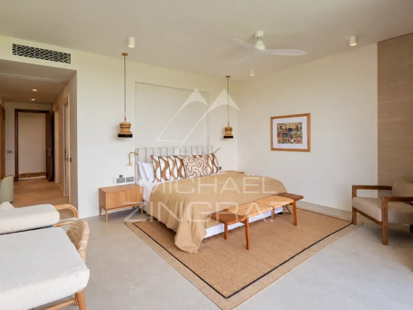 Bedroom in a contemporary villa with bed, armchairs and modern decor.