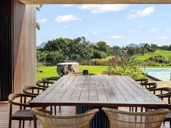 Terrace of a modern villa with a large dining table and views of the golf course and swimming pool.