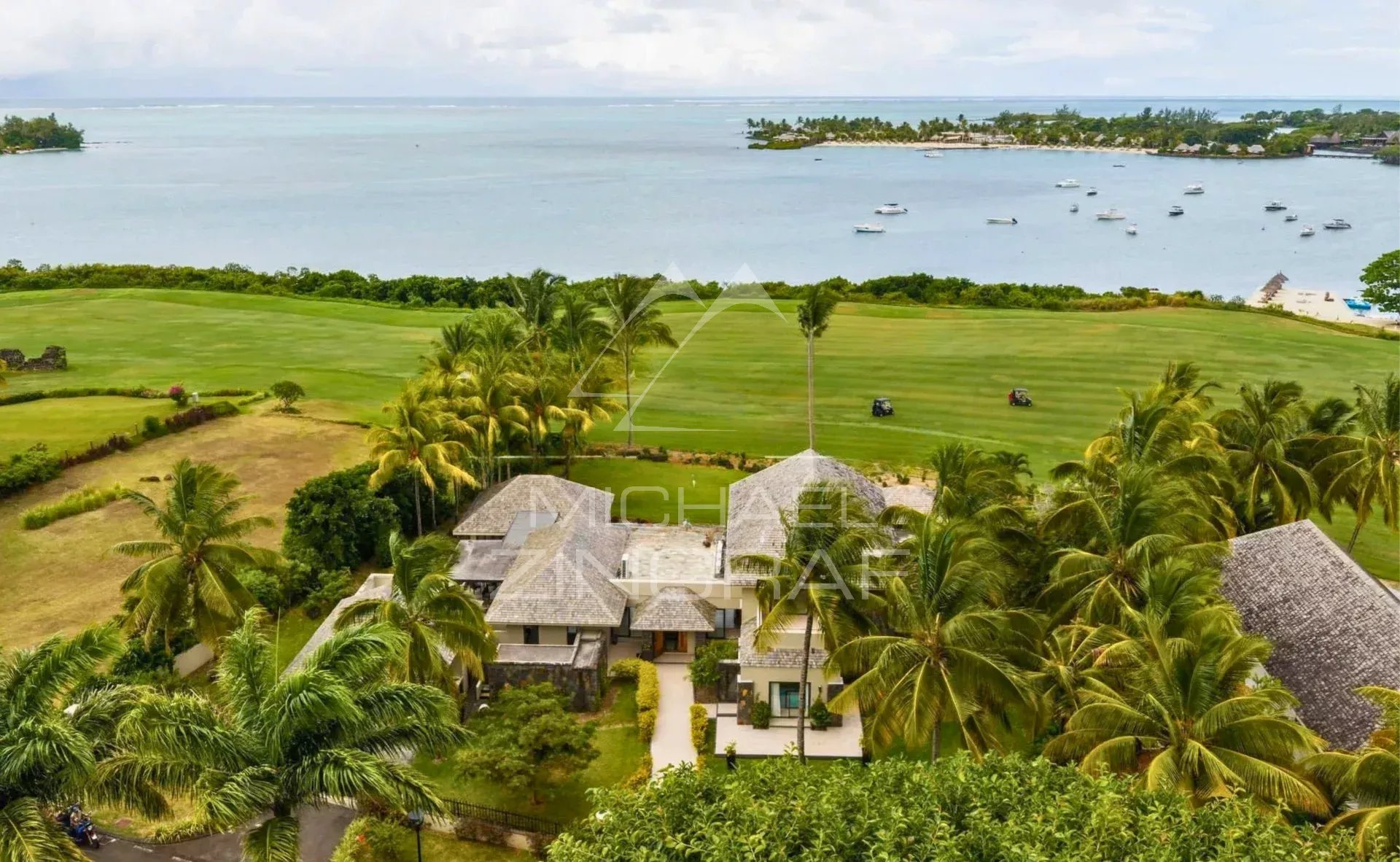 Villa d’Exception à Beau Champ Vue aérienne d'une villa mauricienne avec piscine, golf et lagon turquoise en arrière-plan.