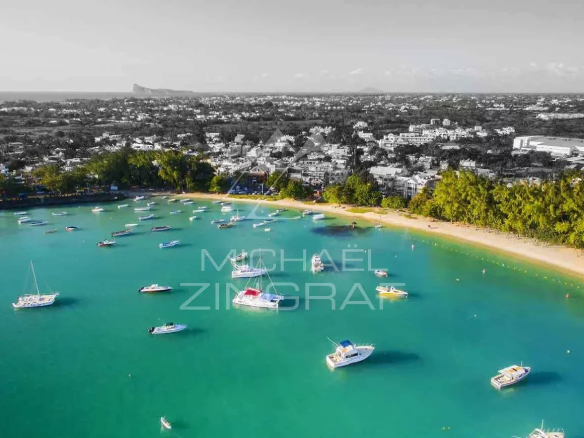 Vue aérienne de Grand Baie avec des bateaux dans l'eau turquoise et des plages de sable.