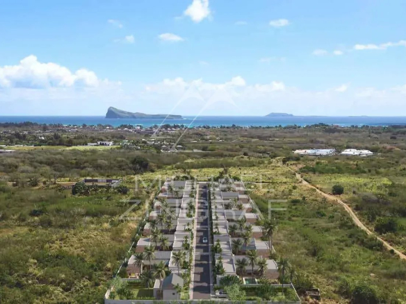 Vue aérienne d'une résidence de villas à Grand Baie, Île Maurice, avec montagnes et mer en arrière-plan.