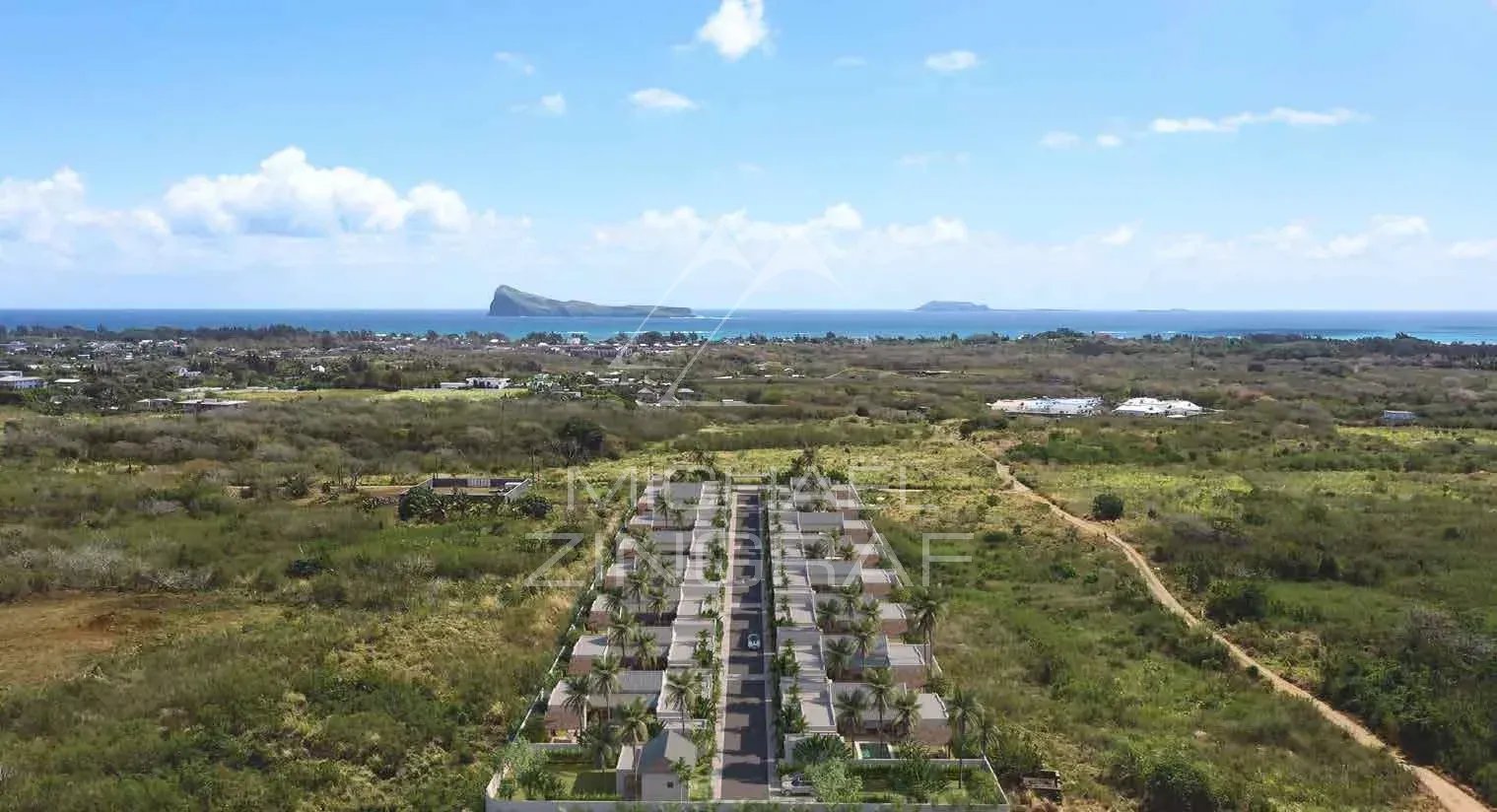 Résidence de villas à Grand Baie Vue aérienne d'une résidence de villas à Grand Baie, Île Maurice, avec montagnes et mer en arrière-plan.