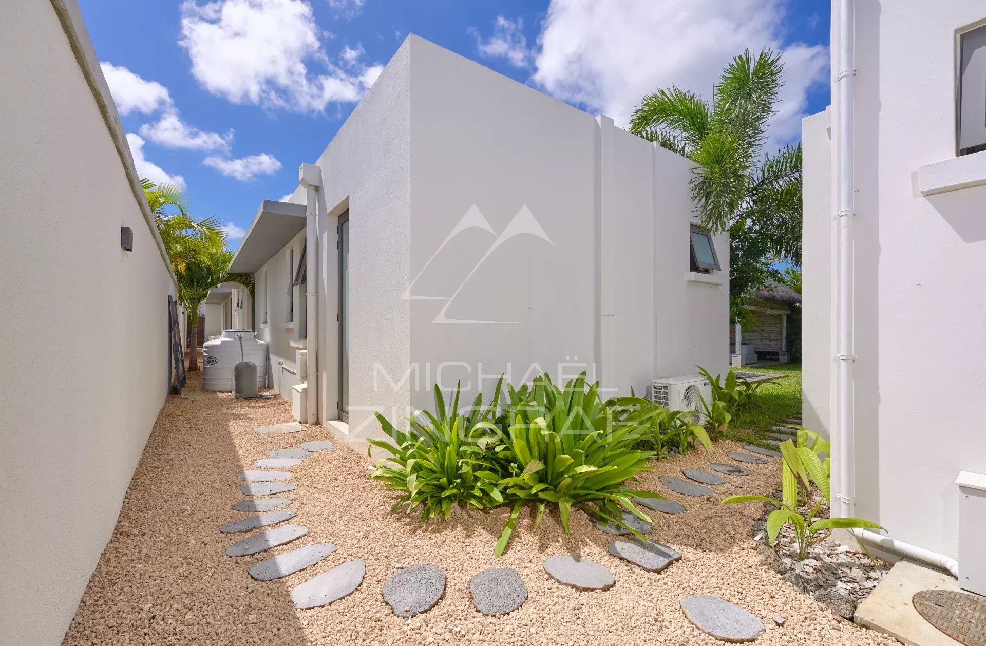 Allée menant à une villa moderne avec jardin tropical à Grand Baie.