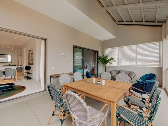 Terrasse d'un penthouse avec vue mer à Pereybere, Ile Maurice, mobilier en bois et chaises confortables.