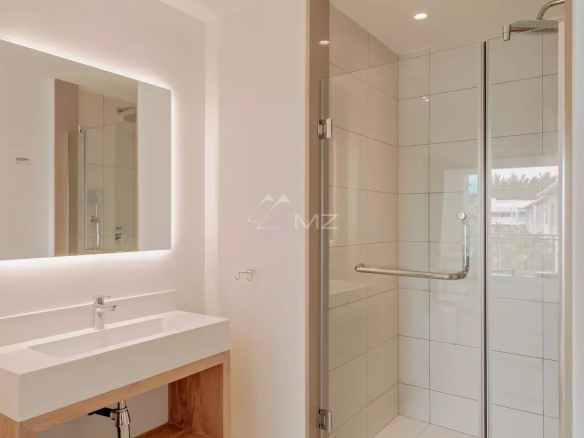 Salle de bain moderne avec douche et miroir éclairé dans un penthouse à Pereybere, Ile Maurice.