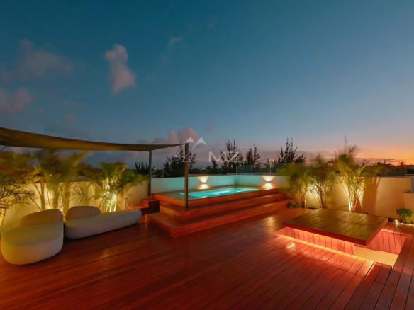 Penthouse avec piscine et terrasse en bois à Pereybere, Île Maurice, au crépuscule.