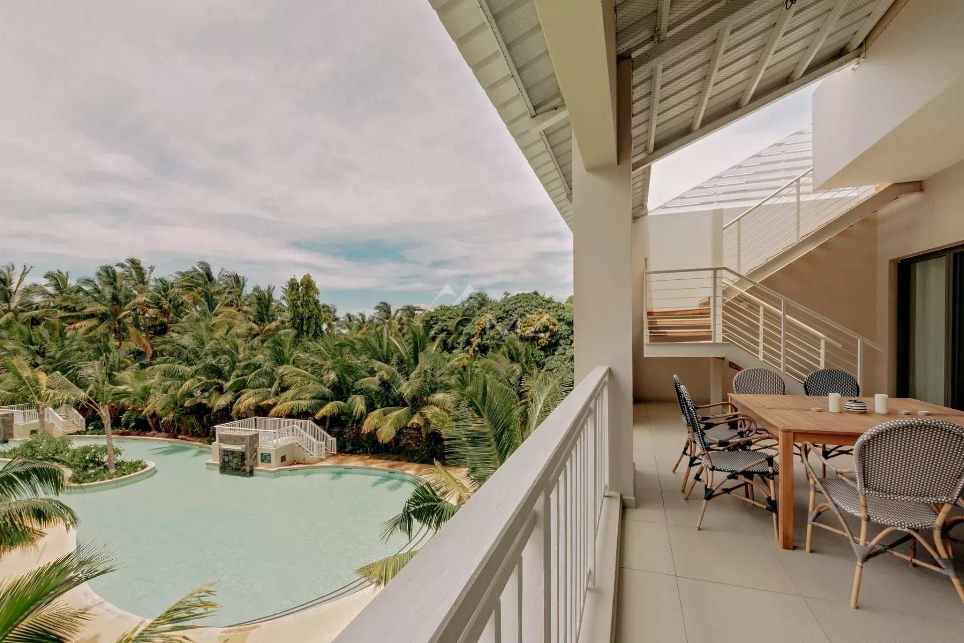 Penthouse avec vue sur la mer à Pereybere Terrasse d'un penthouse avec vue sur la mer et la piscine, entourée de palmiers à Pereybere, Ile Maurice.