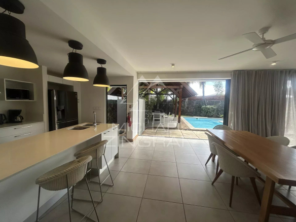 Intérieur d'une villa avec cuisine ouverte et salle à manger, vue sur la piscine extérieure.