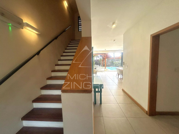 Intérieur d'une villa avec escalier et accès à une salle à manger.