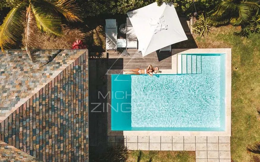 Villa avec piscine à Rivière Noire Vue aérienne d'une villa avec piscine, transat et parasol, entourée de verdure.