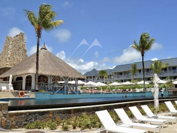 Vue d'un complexe résidentiel avec piscine et palmiers, situé à Azuri Golf and Beach Resort à Haute Rive.