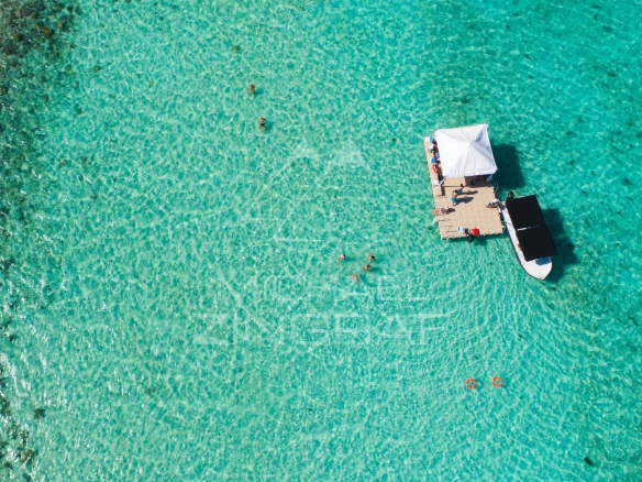 Vue aérienne d'un ponton avec des personnes et un bateau sur une mer turquoise