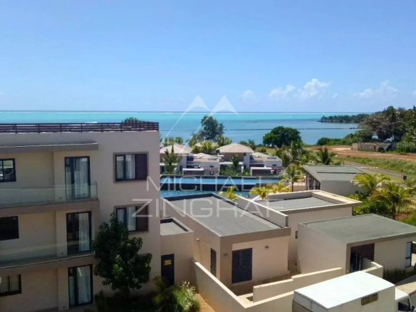 Vue panoramique depuis un penthouse avec mer en arrière-plan et bâtiments environnants.