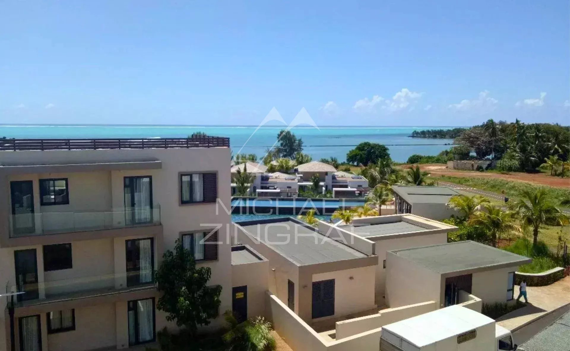 Vue panoramique depuis un penthouse avec mer en arrière-plan et bâtiments environnants.