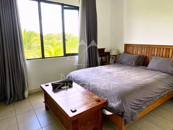 Chambre d'un penthouse avec lit double et fenêtre donnant sur un paysage verdoyant.