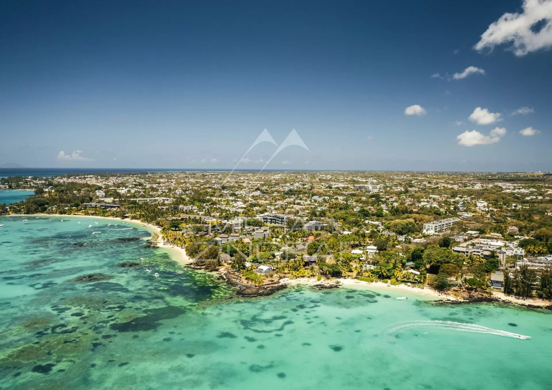 Vue aérienne de Pereybere avec mer turquoise et villas en bord de plage.