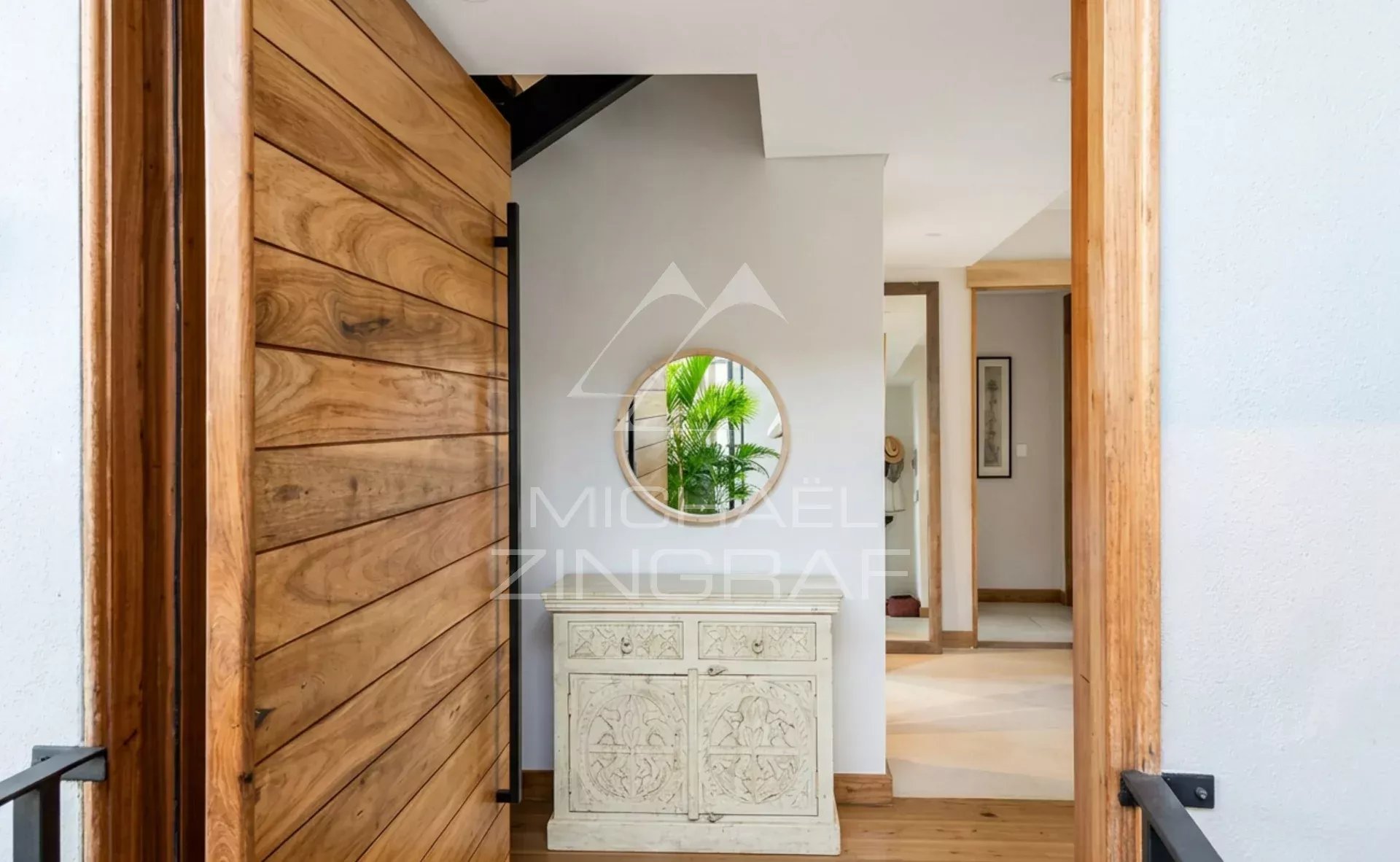 Entrance to the penthouse at Pointe aux Canonniers Entrance to a modern penthouse with a wooden piece of furniture and a round mirror.