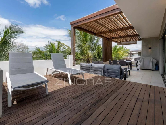 Penthouse terrace with sun loungers and outdoor furniture, surrounded by greenery.