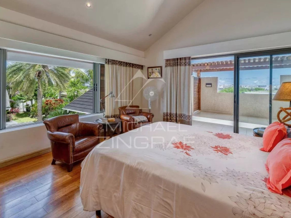 Chambre d'une villa moderne avec lit, fauteuils et vue sur l'extérieur à Grand Baie.