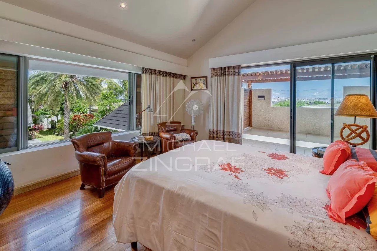 Chambre d'une villa moderne avec lit, fauteuils et vue sur l'extérieur à Grand Baie.