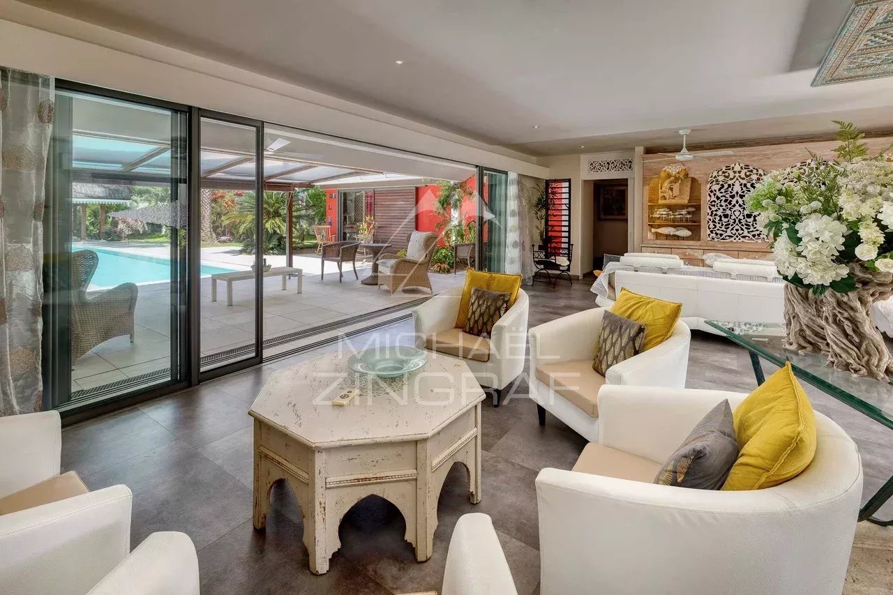 Intérieur d'une villa moderne avec salon lumineux et accès à la piscine.